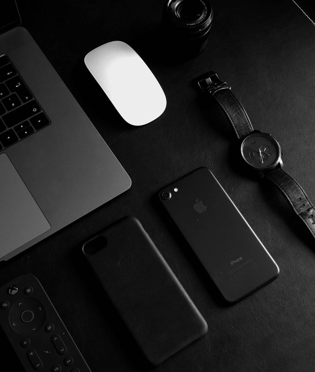 Werkplek van de studio met laptop, telefoon en apparatuur op een donker bureau