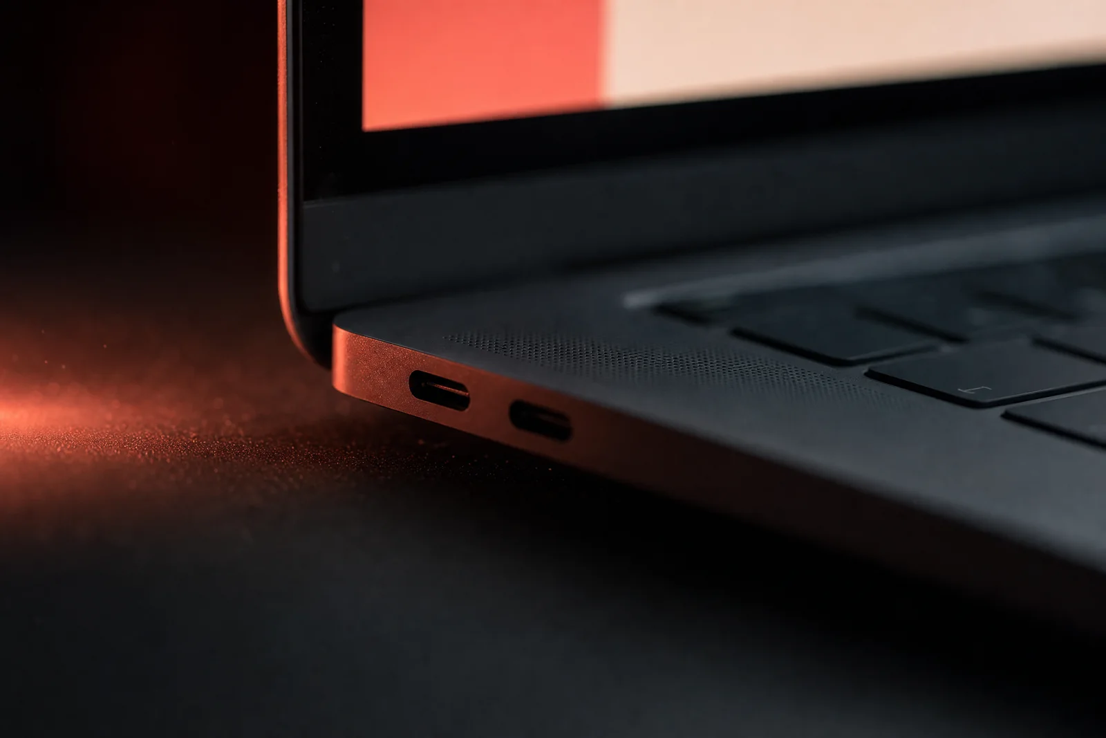 Detail van een laptop in koraalrood studiolicht
